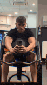 a man in a black shirt is taking a picture of himself in a gym