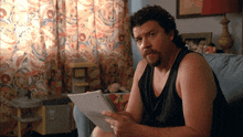 a man sitting on a couch holding a piece of paper with a sticker on it that says ' a '