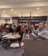 a group of girls are sitting on a couch watching a tik tok video