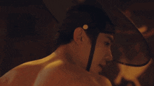 a man without a shirt is wearing a helmet with a black band around his head