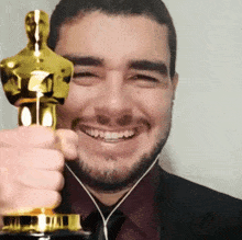 a man in a suit and tie is holding an oscar statue and smiling