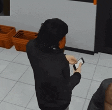 a man in a black sweater is using a cell phone