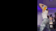 a woman in a white tank top is dancing in a room with a sign that says kee on it .