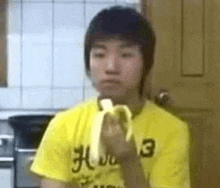 a young man is eating a banana in a kitchen .