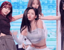 a group of women are dancing on a stage with a blue background