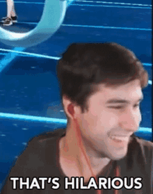 a man wearing ear buds is smiling and says `` that 's hilarious '' .