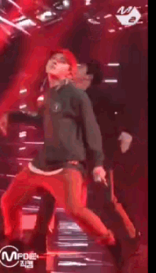 a man in a green shirt is dancing on a stage with a microphone in his hand