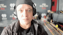 a man wearing headphones is making a funny face in front of a wall that says iheart radio