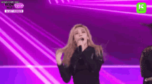 a woman is singing into a microphone while dancing on a stage .