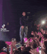 a man is standing on a stage in front of a crowd with a tiktok watermark