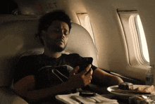 a man sitting on an airplane looking at his cell phone