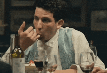 a man sitting at a table with a bottle of wine and glasses