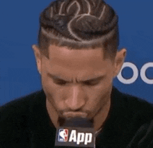 a man with a braided hairstyle is sitting in front of a microphone .