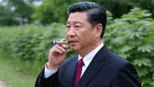 a man in a suit and tie smoking a cigar outside