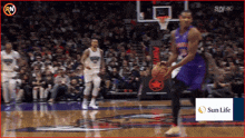 a basketball player dribbles a basketball in front of a sun life advertisement