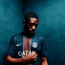 a man wearing a blue shirt that says qatar