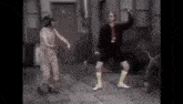 a man and a woman are dancing on a sidewalk in front of a building .