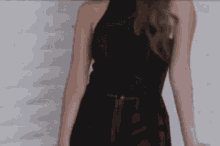 a woman in a black dress is standing in front of a wall