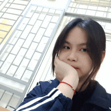 a girl with a red bracelet on her wrist is taking a selfie