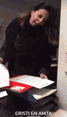 a woman is holding a piece of paper in front of a box that says cristi en amta on it