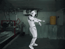 a robot is standing in a room with a yellow trash can in the background