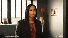 a woman is standing in a room with a nbc logo on the bottom right