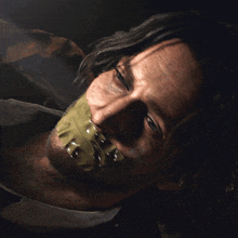 a man with duct tape on his mouth is laying down in the dark