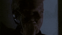 a man is talking on a cell phone in the dark while holding his hand to his face .