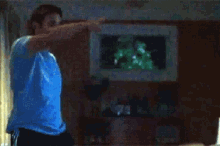 a man in a blue shirt is dancing in front of a tv
