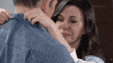 a woman is crying while hugging a man in a blue shirt .