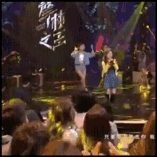 a group of people are watching a concert with chinese writing on the screen