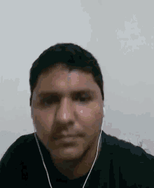 a man wearing earbuds is looking at the camera .