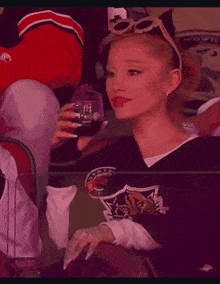 a woman in a hockey jersey is drinking a glass of soda