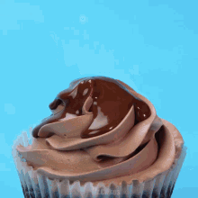 a cupcake with chocolate frosting is being sprinkled with a chocolate ball