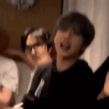 a group of people are standing next to each other in a room and laughing .