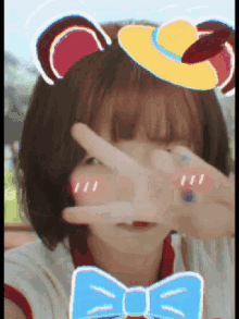 a girl wearing a bow tie and a hat covering her face with her hands
