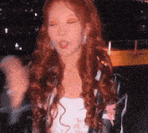 a woman with long red hair is wearing a white top and a black jacket .