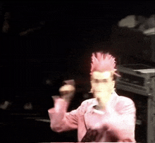 a man with a pink mohawk is dancing on stage .