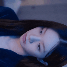 a close up of a woman 's face with a blue shirt on