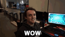 a man sitting in front of a computer with the word wow written on his shirt