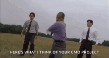 three men in suits and ties are standing in a field and one of them is dancing .