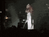 a woman in a white dress and black gloves is singing into a microphone