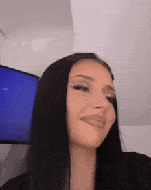a woman with long black hair is making a funny face in front of a television
