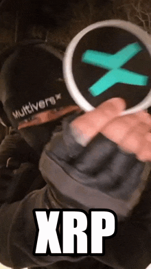 a person wearing a hat that says multiverse holds a circle with a green x in it