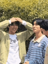 a group of young men are standing next to each other and one of them is making a heart with his hands .
