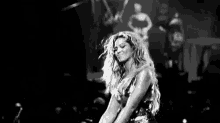 a black and white photo of a woman singing into a microphone .