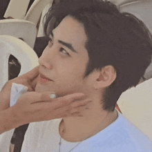 a person is touching a young man 's face with a napkin .