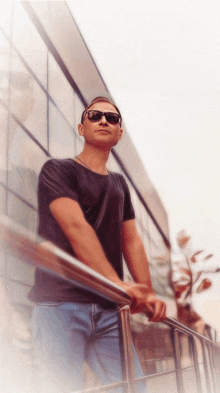 a man wearing sunglasses leans against a railing