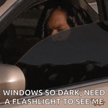 a woman is sitting in a car with her head out the window and a flashlight to see her .