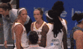 a group of female basketball players are huddled together with one wearing a jersey that says howard